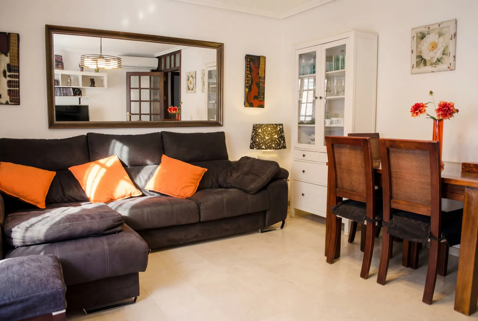 SALÓN — Sofá amplio, gran espejo, mueble vitrina y mesa de comedor con luz natural.